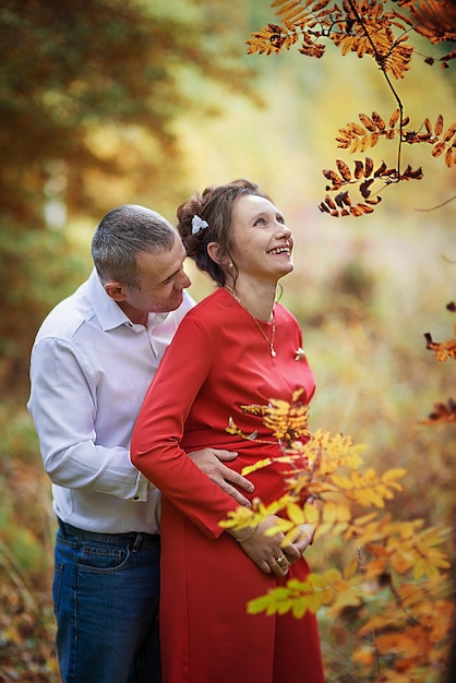 Pregnant woman with her husband in the autumn park