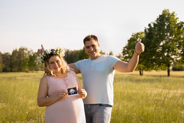 Pregnant woman with her husband on a field with flowers