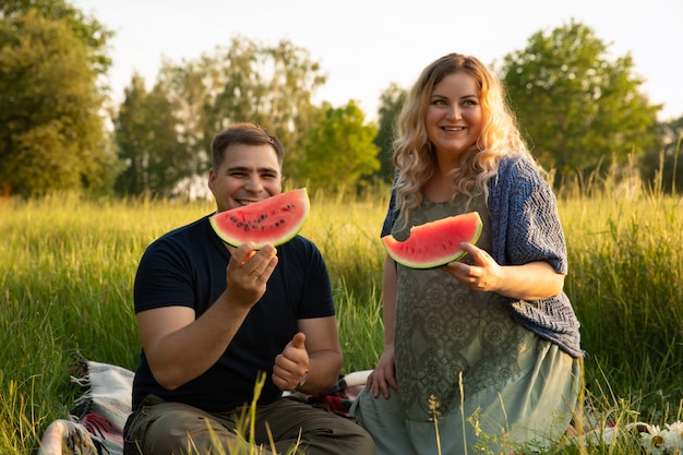 Pregnant woman with her husband on a field with flowers.