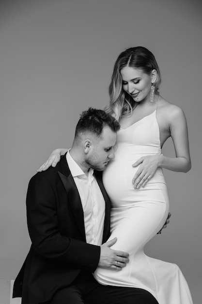 Pregnant woman with her husband holding her belly black and white photo