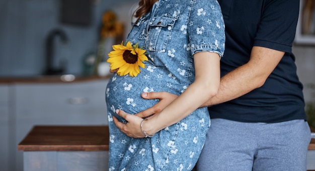 Pregnant woman with her husband standing at the table in the kitchen