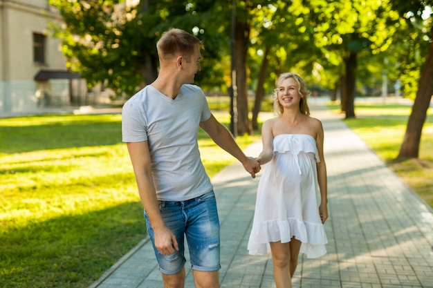 Pregnant woman with her husband walking in a park