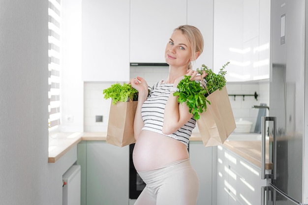 Pregnant woman with packages of fresh herbs green smoothies the concept of wholesome and healthy food for pregnant women