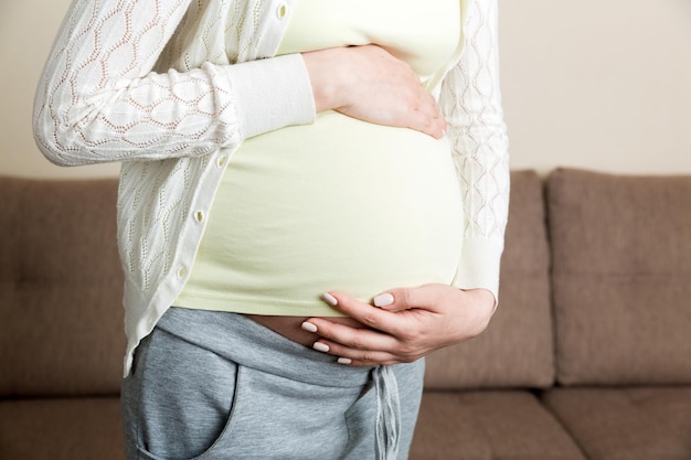 Pregnant woman with painful belly on sofa at home