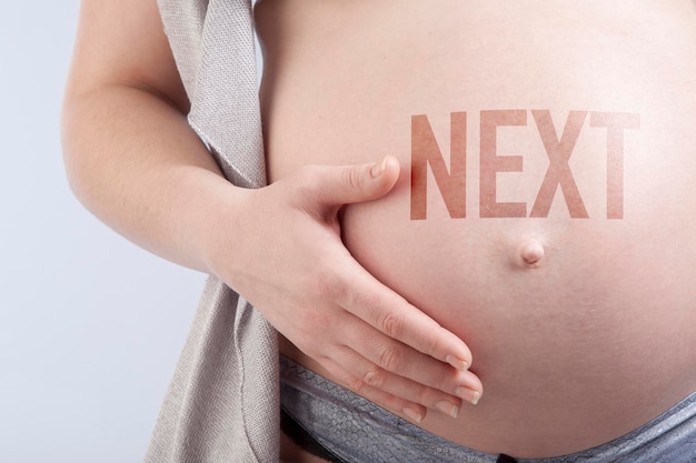 Pregnant woman with title next on her belly