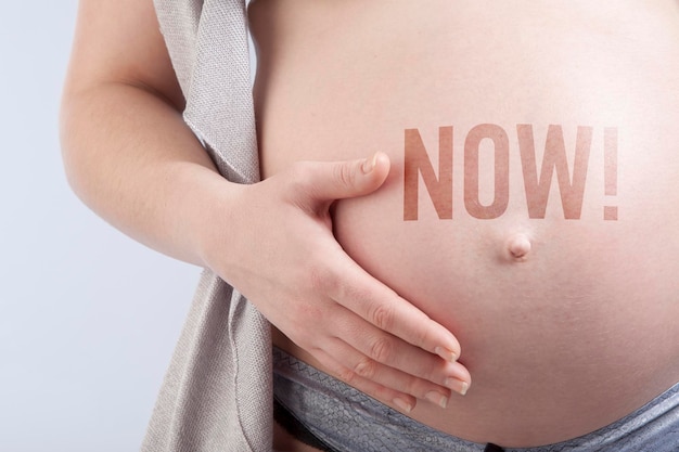 Pregnant woman with title now on her belly