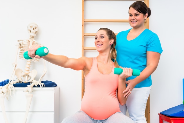 Pregnant woman working out with dumbbells in physical therapy