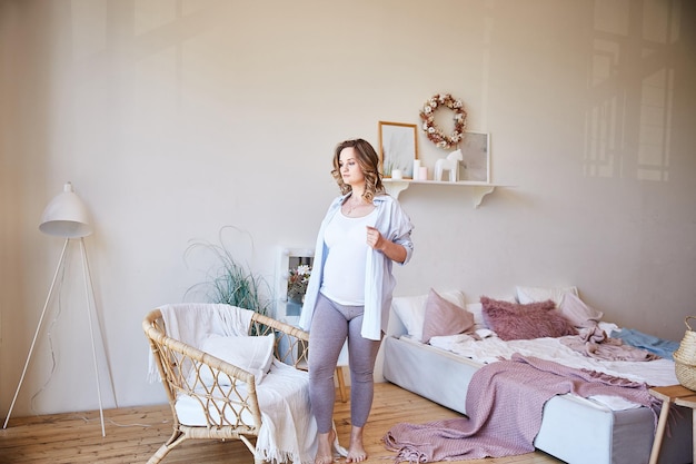 pregnant young woman got out of bed in a bedroom in her big house.