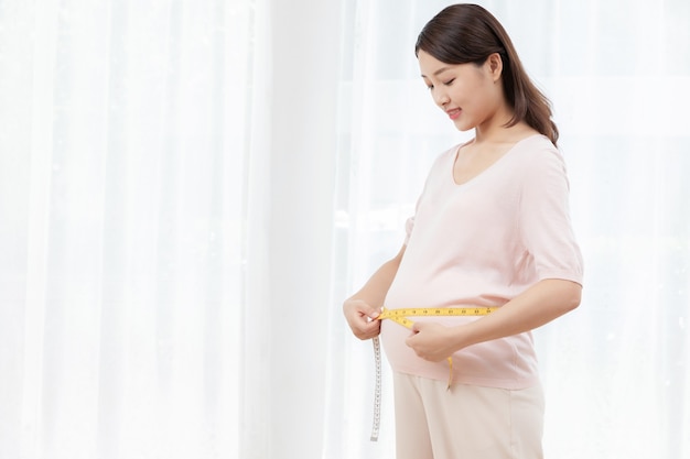 Pregnant young woman measuring her belly