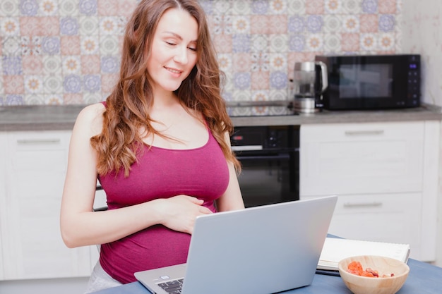 Pregnant young woman using a laptop computer The concept of work from home or online learning