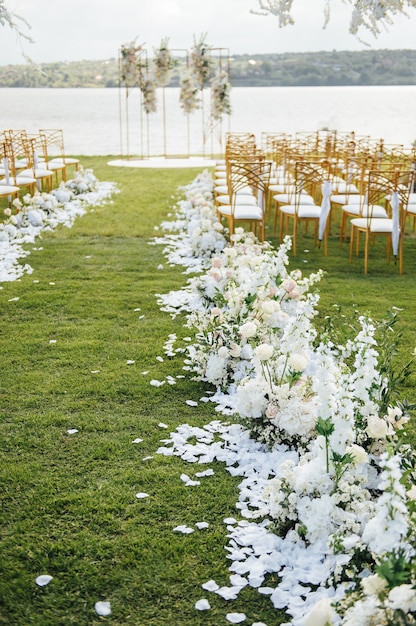 Premium arch for wedding ceremony for newlyweds on the river bank with wisteria trees. empty chairs and umbrellas