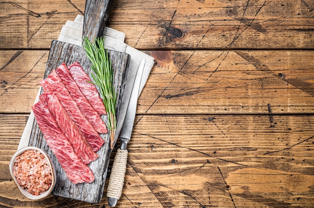 Premium Rare Slices of Wagyu A5 beef with high marbled texture. wooden background. Top view. Copy space.