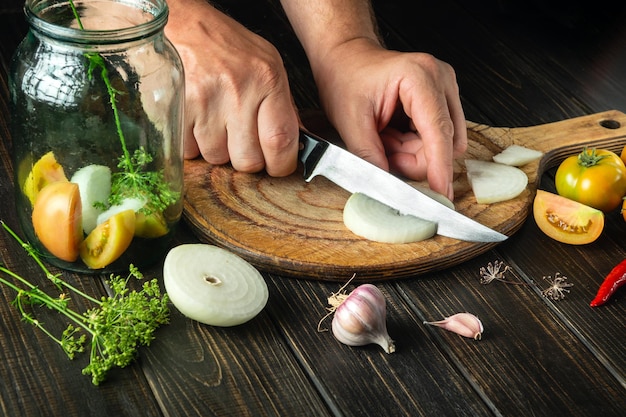 Preparation of canned vegetable salad Chef hands cut onion on a cutting board with a knife