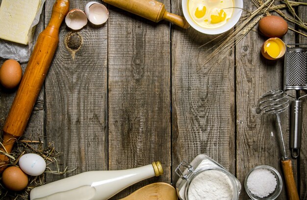 Photo preparation of the dough. ingredients for the dough - milk, flour, eggs and different tools . on a wooden table.  free space for text . top view