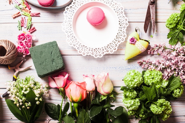 Preparation of flower box with macaroons, top view of florist workplace