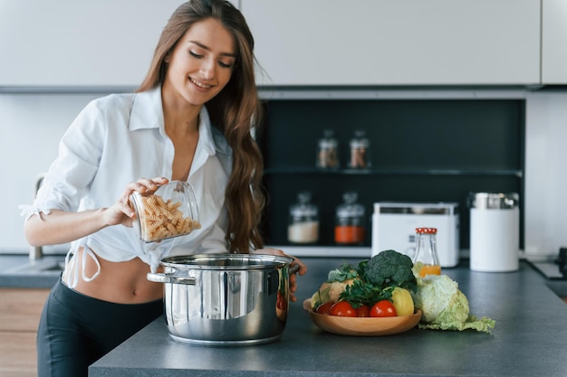 Preparation of meal in bowl Young european woman is indoors at kitchen indoors with healthy food