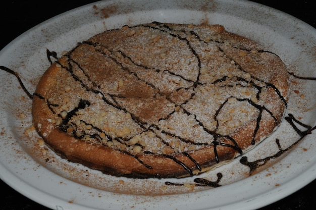 Preparation of an orange sponge cake sprinkling icing sugar on the decoration