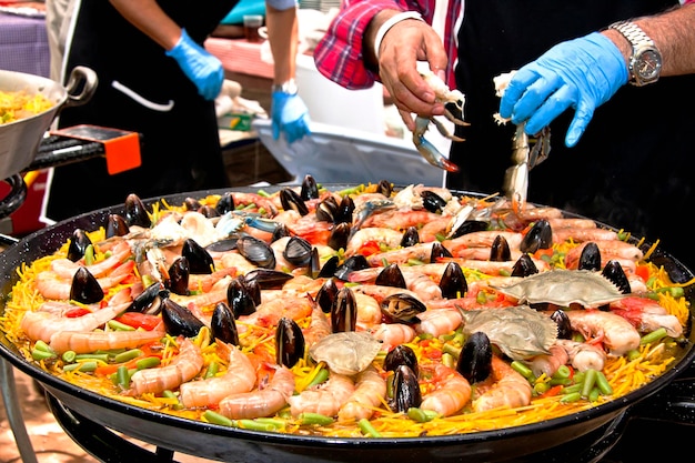 Preparation of Paella with prawns, mussels, fish and octopus in a paellera, Spanish food, tourism