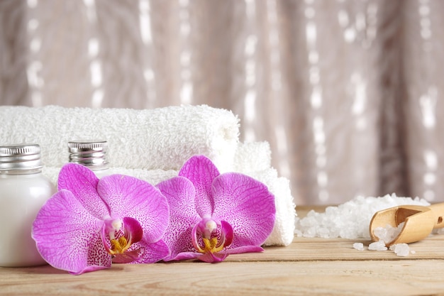 Preparation for spa procedures, salt, towels, lotion and bright flowers of orchids on the table