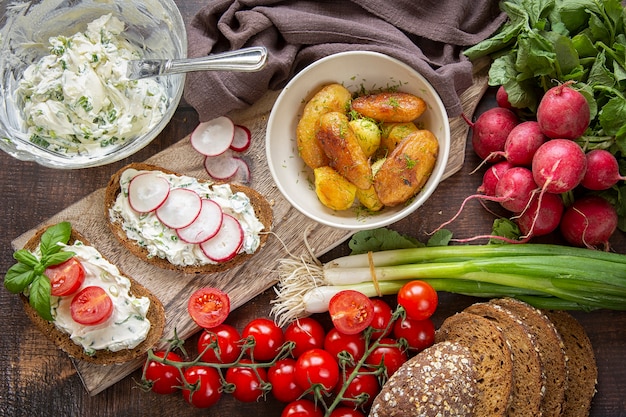 Preparation of summer sandwiches cottage cheese with green onions, radishes and tomatoes. keto diet ,Whole fried potatoes.