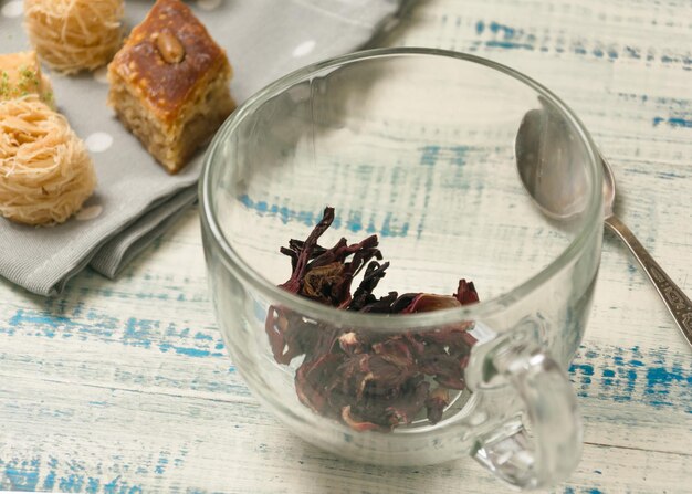 Preparation for tea Dry tea in a cup on a background of oriental sweets on a wooden background