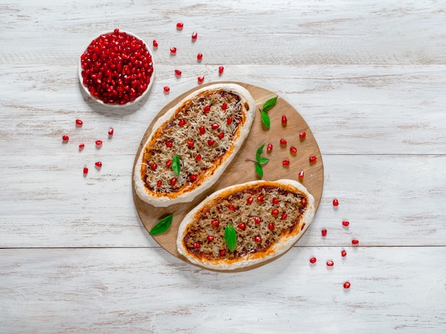 Preparation of traditional Arabic pizza manaqish with meat and pomegranate.