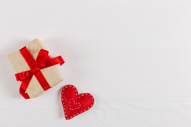 Preparation for Valentine's Day. Red hearts and craft gifts on white wood. Copy space