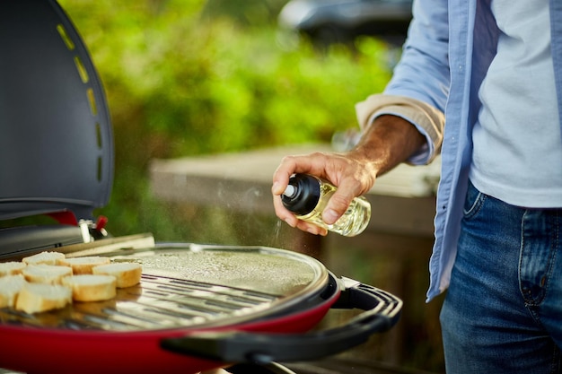 Prepare breakfast with bread roasting bruschetta and man spraying oil on the barbecue gas grill