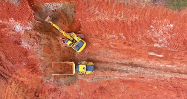 To prepare the ground for construction an excavator loads earth dump trucks and moves soil so that it can be ready for construction on a construction site