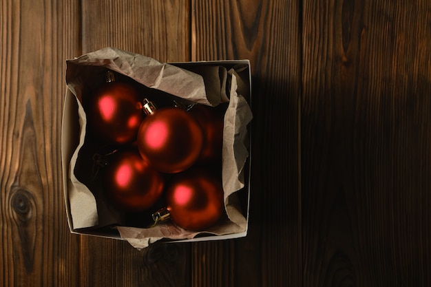 Preparing for Christmas. Decorations for the Christmas tree. Red christmas balls in a box on a wooden table