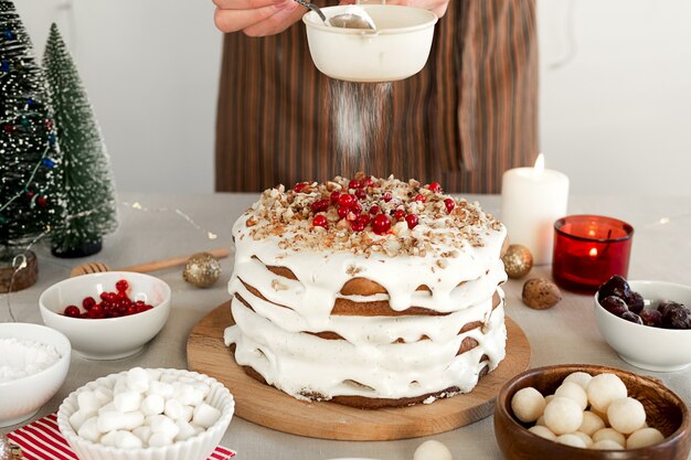 Preparing food Christmas dinner Womens hands are sprinkled with powdered sugar through sieve cake