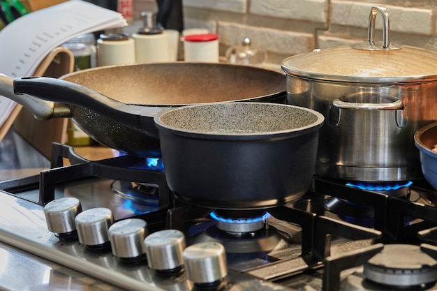 Preparing food in frying pan and casseroles on the gas stove in the kitchen