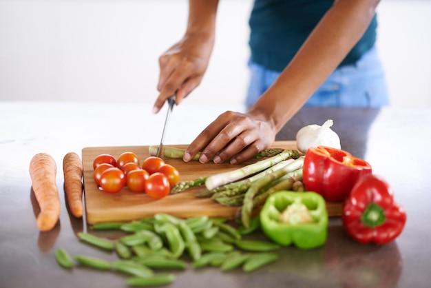 Preparing a healthy and wholesome meal Cropped closeup shot of a woman cutting up vegetables on a cutting board