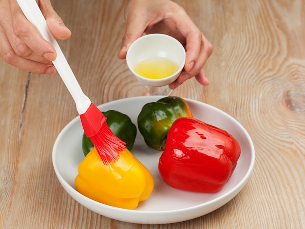 Preparing peppers - man 's hands smearing vegetables with oil