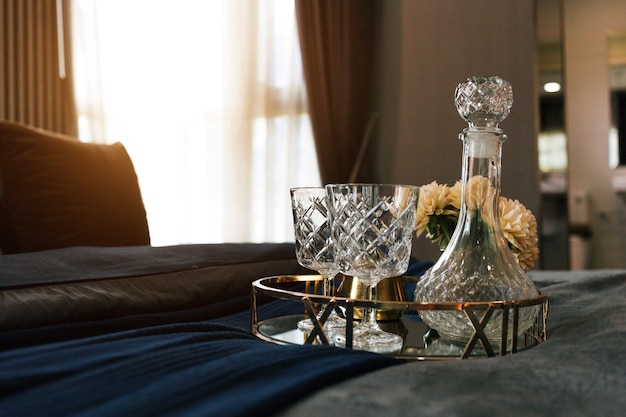 Preparing romantic dinner with bottle and glass of liquid on bed