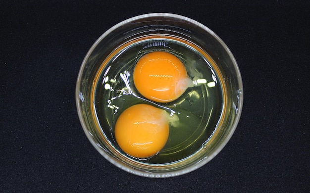 Preparing Scrambled Eggs Two Raw Eggs In A Glass Plate On Black Surface Top View