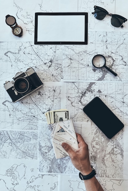 preparing to travel. close up top view of man holding passport and money with smart phone