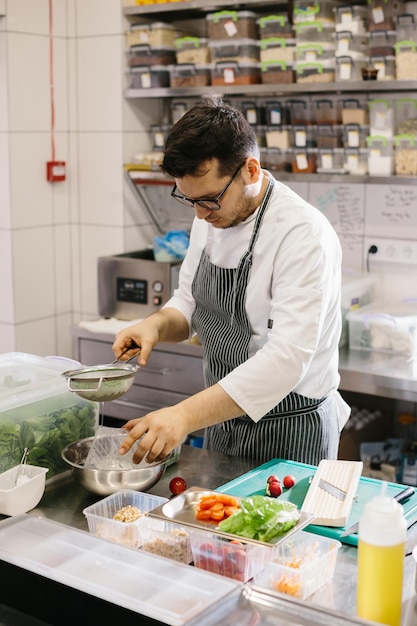 Preparing vegetables for a delicious bowl dish a male chef in a contemporary restaurant kitchen