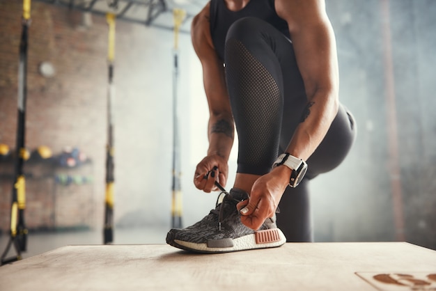 Preparing for workout cropped photo of beautiful young woman in sports clothing tying her shoelaces