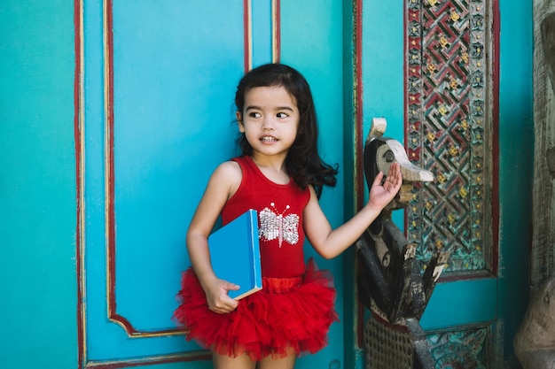 Preschool Asian cute girl in red dress with book