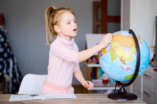 Preschool girl looking at earth globe at home