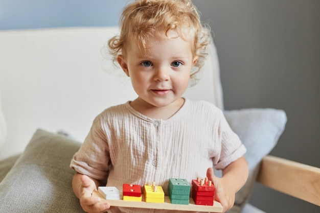 Preschooler's logical skills Creative imagination play Blonde wavy haired little blonde baby girl palying with wooden sorter toys at home interior