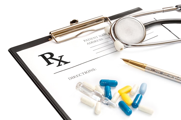 Prescription form on the clipboard with stethoscope and pills Isolated on white Medical concept