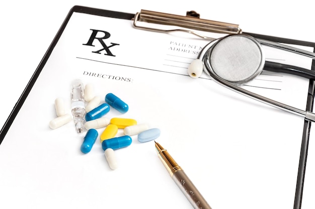 Prescription form on the clipboard with stethoscope and pills. Isolated on white. Medical concept.