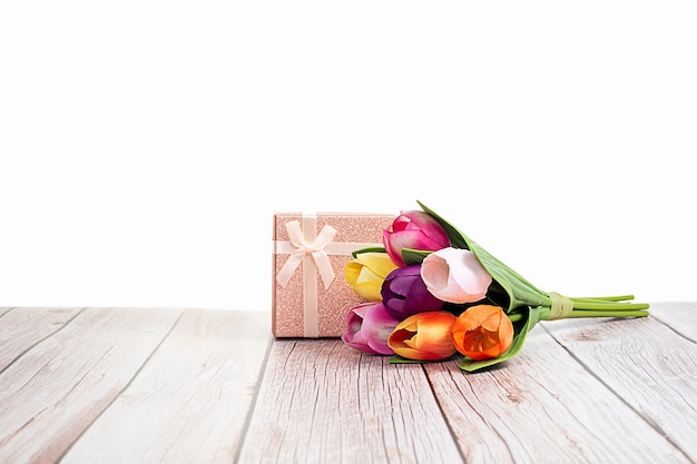 Present box and tulips on wooden rustic table with white background with space for text.