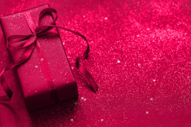 Present box with blue bow on viva magenta background Festive concept Color of the year 2023