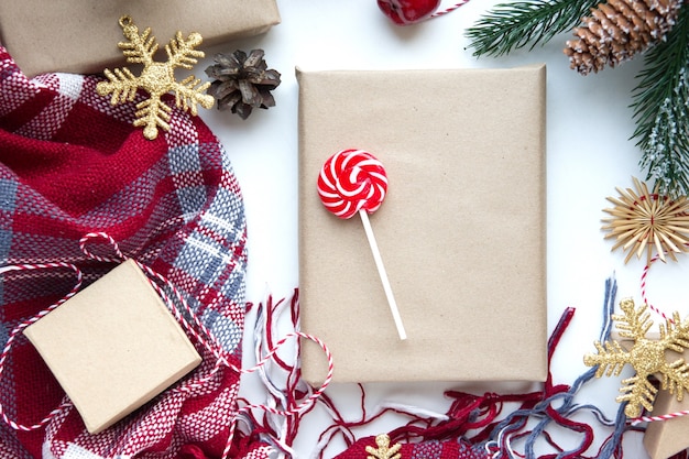 Present in brown craft paper, boxes, candy, plaid and Christmas decoration on table. Copy space. Eco friendly New Year concept