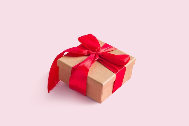 Present craft box with red ribbon bow, on pink