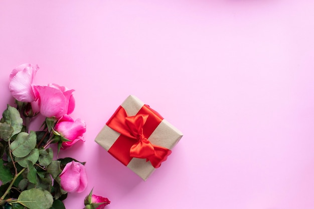 present tied with red ribbon and pink roses bouquet. valentine's day, christmas, mother's day, birthday presents. Greeting card concept