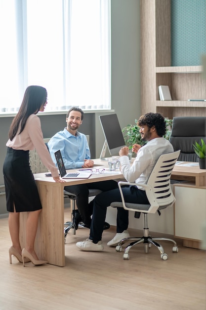 Presentation. Long-haired brunette talking with business partners in the office